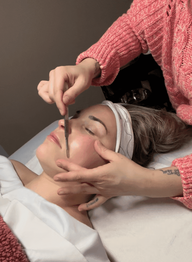 Esthetician applying facial treatment to a relaxed female client.